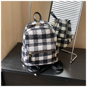Detail of black and white plaid tweed backpack with leather straps and gold zippers