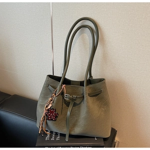 Detail of olive green suede tote bag with drawstring metal buckle and bear charm