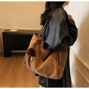 Brown suede tote bag detail with decorative pom-pom and beaded tassel on model