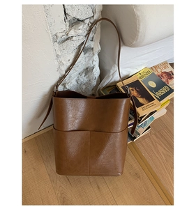 Détail du sac seau marron caramel montrant le cuir grainé poli et la poche frontale