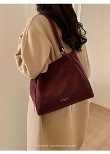 Model wearing dark burgundy leather tote bag with a minimalist sophisticated retro vibe