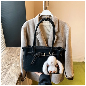 Close-up of black tote bag with white contrast stitching and cute plush rabbit charm