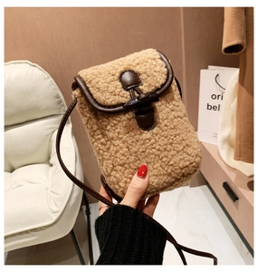 Detailed close-up of a teddy sherpa crossbody phone bag with horn buckle and leather trim