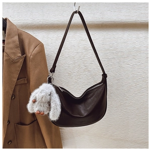 Detail view of a dark brown half-moon shoulder bag with a cute white bunny keychain