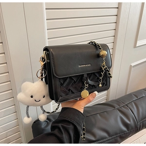 Detail of black woven crossbody bag with gold chain and plush cloud charm accessory