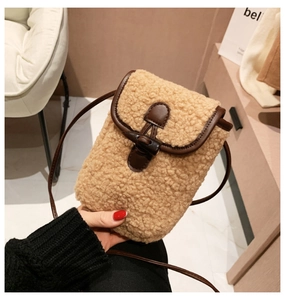 Close-up of camel fleece crossbody bag with brown leather trim and toggle closure