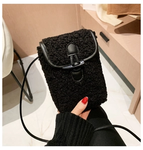 Close-up of black fuzzy faux fur crossbody phone bag with horn buckle and leather trim
