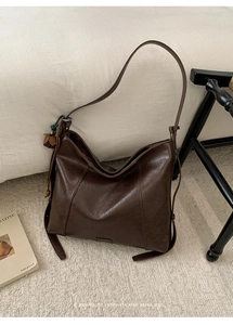 Détail du sac cabas en simili cuir marron foncé avec texture vintage et glands perlés