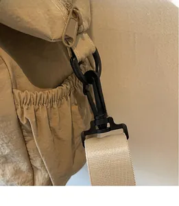 Detail of durable black swivel hook and elastic side pocket on khaki nylon tote bag