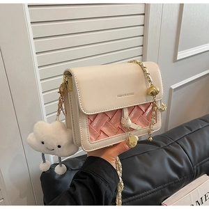 Detail of cream crossbody bag with pink woven flap and gold chain strap and charm