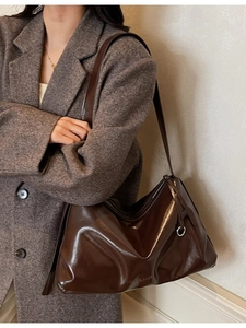 Vintage dark brown leather tote bag with a high-shine finish on a female model