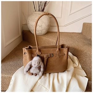 Close-up of vintage brown tote bag with buckle detail and plush rabbit keychain charm