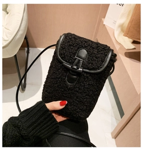 Close-up of black fuzzy faux fur crossbody phone bag with leather trim and horn buckle