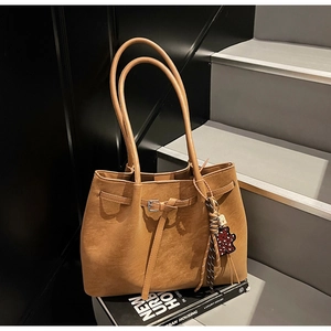 Detail of tan tote bag featuring silver buckles and a leopard print bear pendant