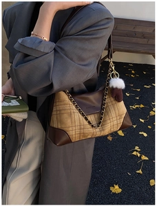 Detail of vintage plaid shoulder bag with leather trim and gold chain on autumn background