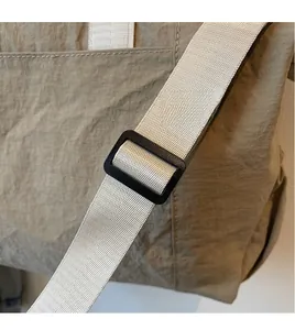 Close-up of adjustable woven nylon shoulder strap and matte buckle on a khaki tote bag