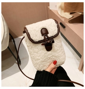 Detail of white teddy fleece bag with brown leather trim and wooden toggle button closure