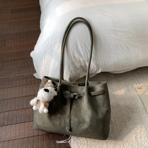 Dettaglio della borsa tote in pelle scamosciata verde oliva con fibbia e ciondolo peluche