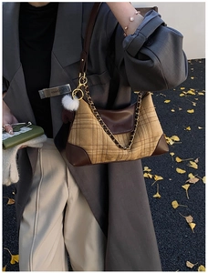Detail of vintage yellow plaid fabric and brown leather stitching with a white fur ball charm