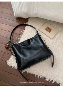 Détail d'un grand sac cabas en cuir noir vintage avec logo et pendentif à pompon marron