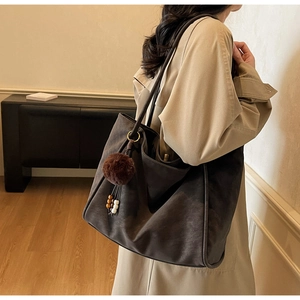 Detailed texture of a large dark brown suede tote bag with decorative bead charm
