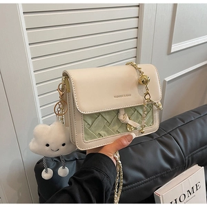Detail of crossbody bag with beige leather, green weave, and cute cloud plush charm