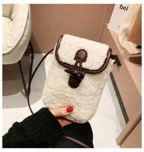 Detail of white faux shearling mini crossbody bag with brown leather trim and toggle button