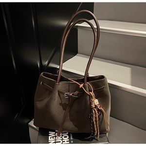 Detail of olive green tote bag featuring brown leather trim and cute bear charm