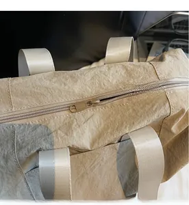 Detail view of smooth zipper closure and textured khaki nylon fabric on tote bag