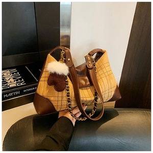 Detail of plaid tote bag featuring leather patchwork and heart shaped furry pendant