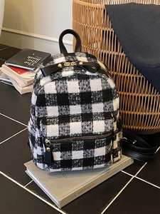Mini plaid backpack with black bow and gold zipper on books in a cozy setting