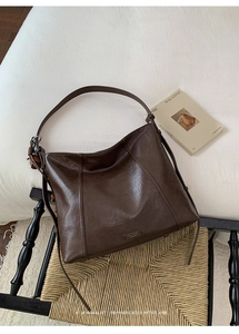 Détail du sac cabas en cuir marron foncé avec logo doré et pendentif en bois tressé