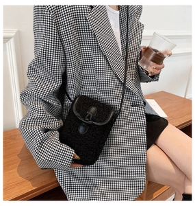 Close-up of black sherpa crossbody phone bag with buckle and leather strap on model