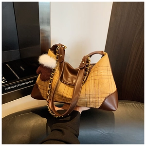 Close-up of retro plaid handbag with brown leather trim and a plush heart charm