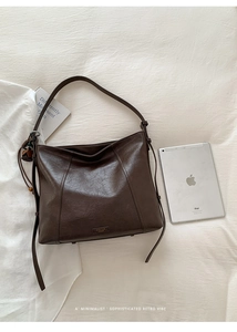 Vue détaillée du sac cabas marron foncé avec texture plissée vintage et pompon décoratif