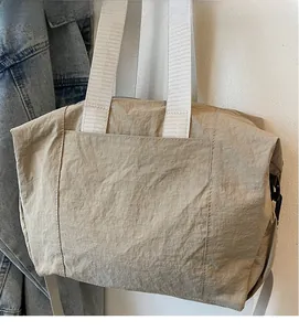Detail of khaki textured fabric shoulder bag with wide white strap and side buckle