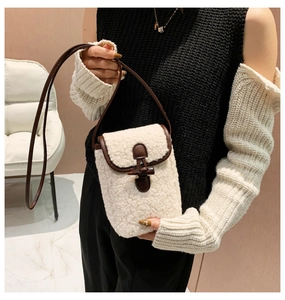 Detail view of cream faux shearling mini bag with brown leather trim and horn button closure