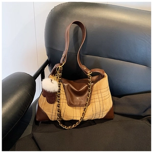 Detail of vintage patchwork handbag with brown leather, plaid fabric and gold chain accents