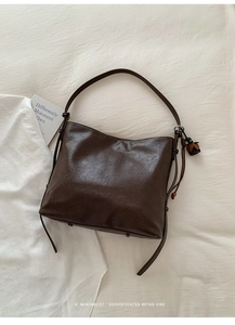 Gros plan détaillé du sac hobo rétro marron foncé avec pompon et texture cuir vintage