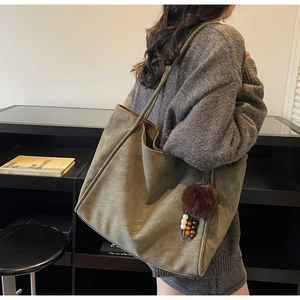 Detail of olive green oversized tote bag with plush charm and beaded tassel accessory