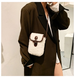 Detailed shot of white sherpa crossbody bag with brown trim and vintage horn buckle