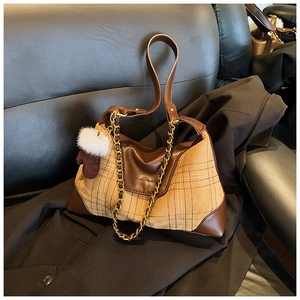 Detail of checkered shoulder bag with faux fur pompom and leather strap on a blazer