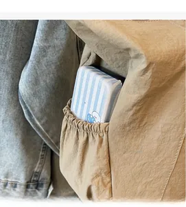 Detail shot of the durable elastic side pocket on a khaki tote bag with a striped item