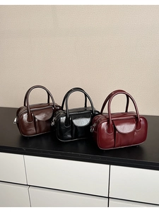 Close-up of three vintage oil wax leather bowling bags in dark brown, black, and burgundy