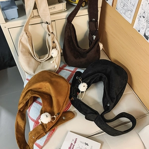 Détail de quatre sacs hobo en beige, marron et noir avec des pompons en peluche