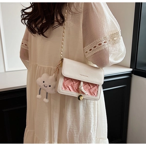Detail of pink woven crossbody bag with gold chain strap and plush cloud charm
