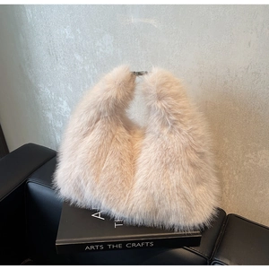 Detail of light beige faux fur handbag featuring a silver metal buckle on a plush texture