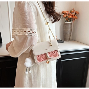 Detail of white leather crossbody bag with pink woven texture and gold chain strap