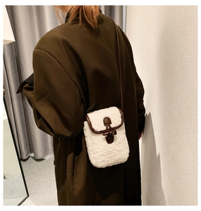 Detailed back view of a white sherpa crossbody bag with brown leather trim on a model