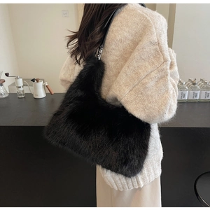 Detail of black faux fur shoulder bag featuring soft texture and leather strap on model
